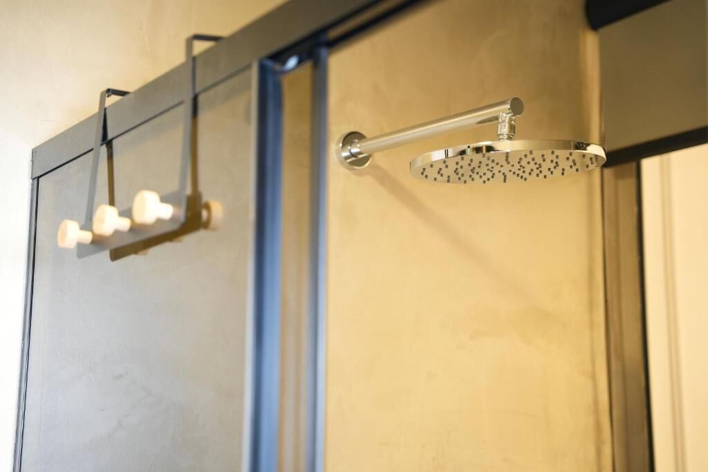 A shower with a handheld showerhead and a wall-mounted faucet.
