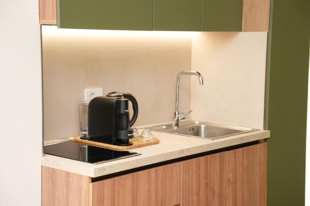 A compact kitchen with a coffee maker, a sink, and a wooden countertop.