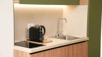 A compact kitchen with a coffee maker, a sink, and a wooden countertop.