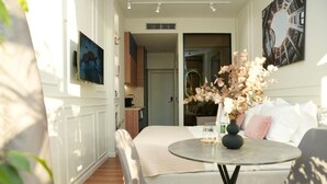 Un salon moderne avec un canapé, une table ronde en verre et un vase rempli de fleurs.