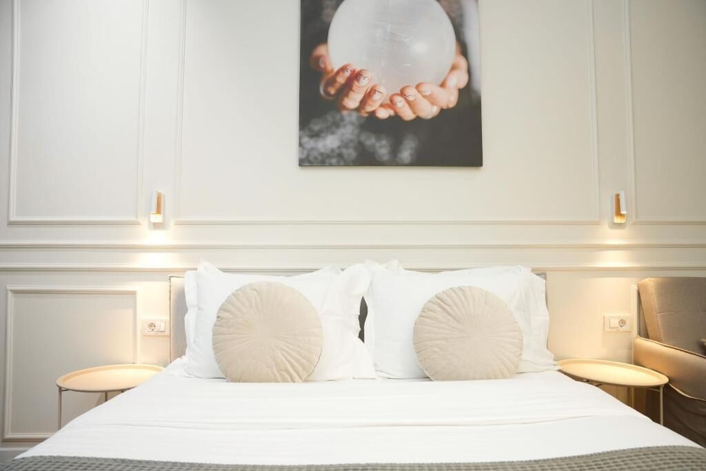 Een hotelkamer met een opgemaakt bed, twee nachtkastjes en een aan de muur hangend schilderij.
