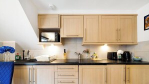 Una cocina moderna con armarios de madera clara, encimera negra y electrodomésticos de acero inoxidable.