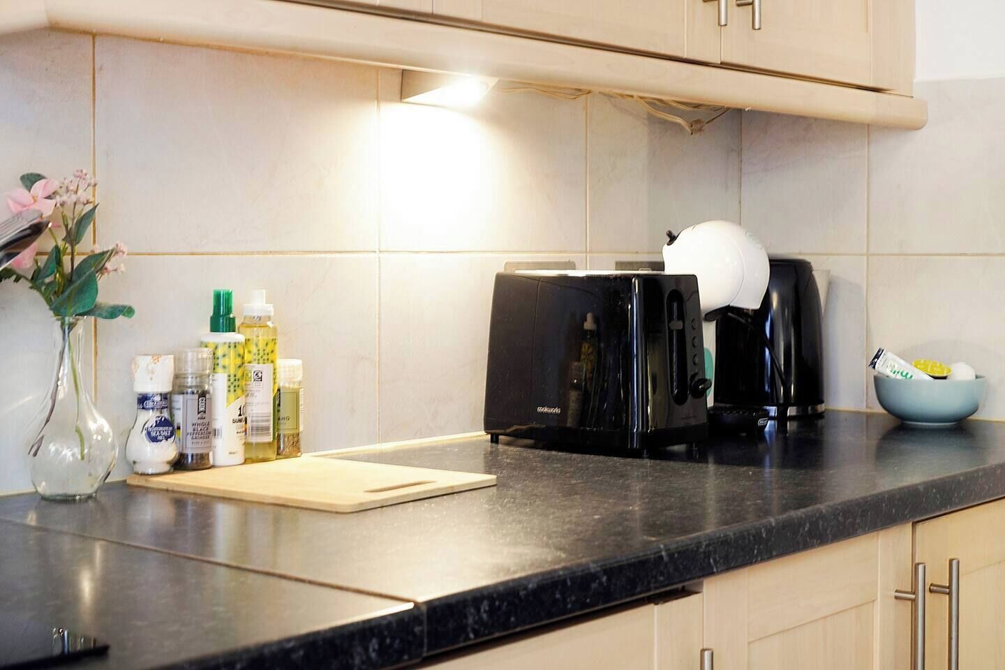 Una cocina con un tostador, una cafetera y un bol sobre la encimera.
