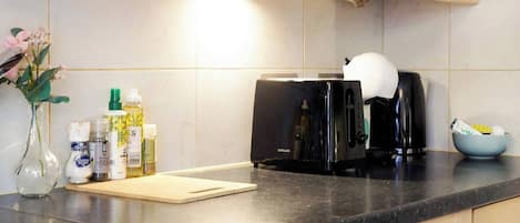 Una cocina con un tostador, una cafetera y un bol sobre la encimera.