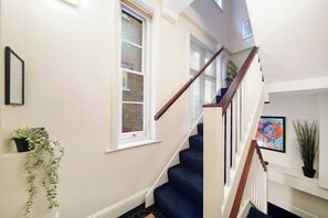 Eine Treppe mit hölzernem Geländer und weißen Wänden, die zu einer oberen Etage führt.