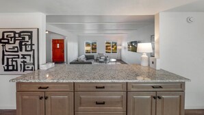 A kitchen with a granite countertop, wooden cabinets, and a view into a living area with a sofa and a dining table. - Pool / 4 BR 2 BA / Davis-Monthan AFB / Renovated (Tucson)