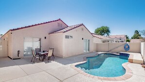 Ein Haus mit Swimmingpool, Terrassenmöbeln und einer überdachten Terrasse.