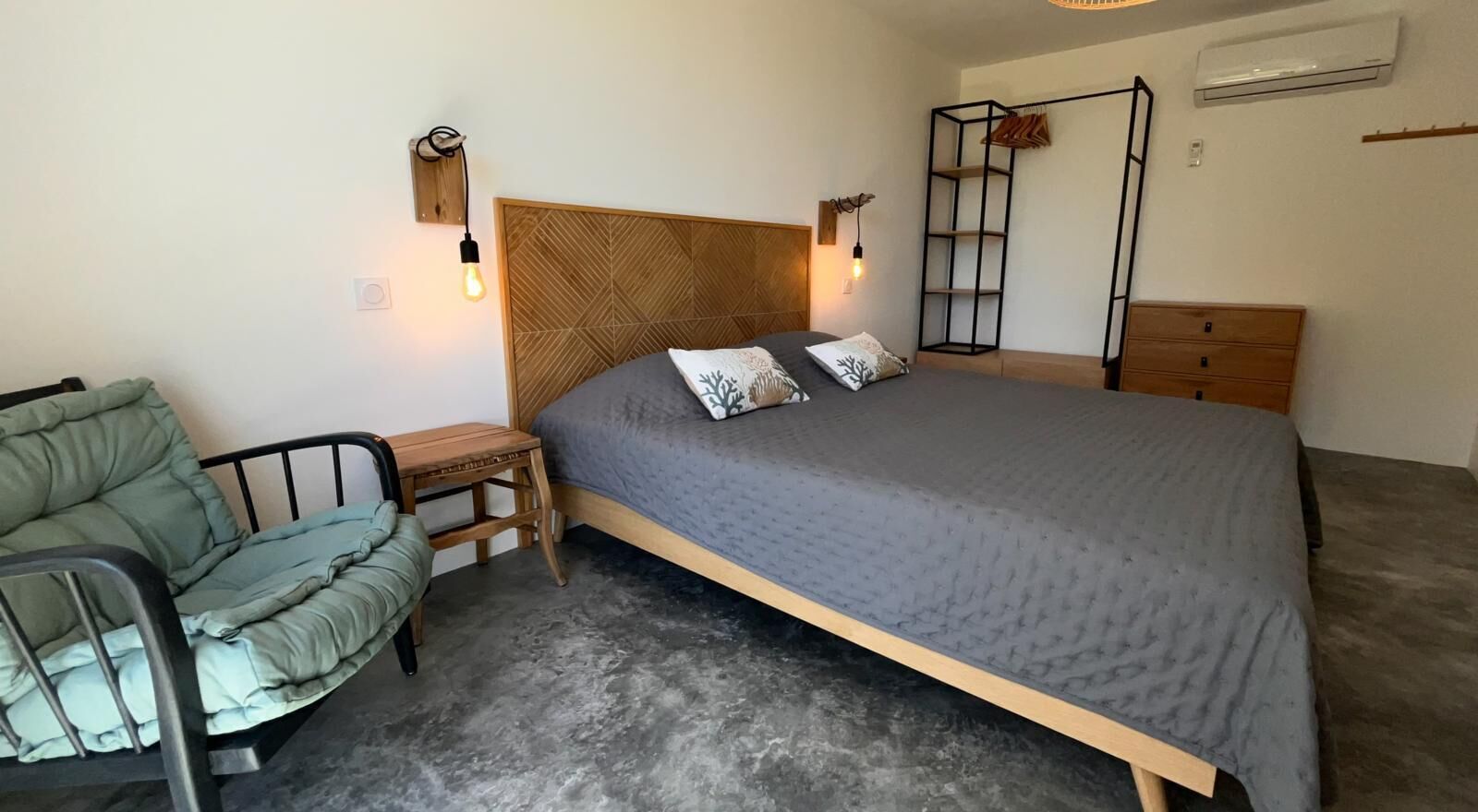 Une chambre à coucher comprenant un lit, une table de chevet, une chaise et une étagère fixée au mur.
