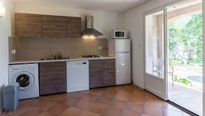 A compact kitchen with a washing machine, dishwasher, microwave, and a small refrigerator. - Villa du Domaine 3bed park view (Sari-Solenzara)
