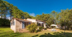 A small house with a tiled roof, a porch, and a patio with outdoor furniture. - Villa du Domaine: 3-Bedroom Villa with Park Views (Sari-Solenzara)