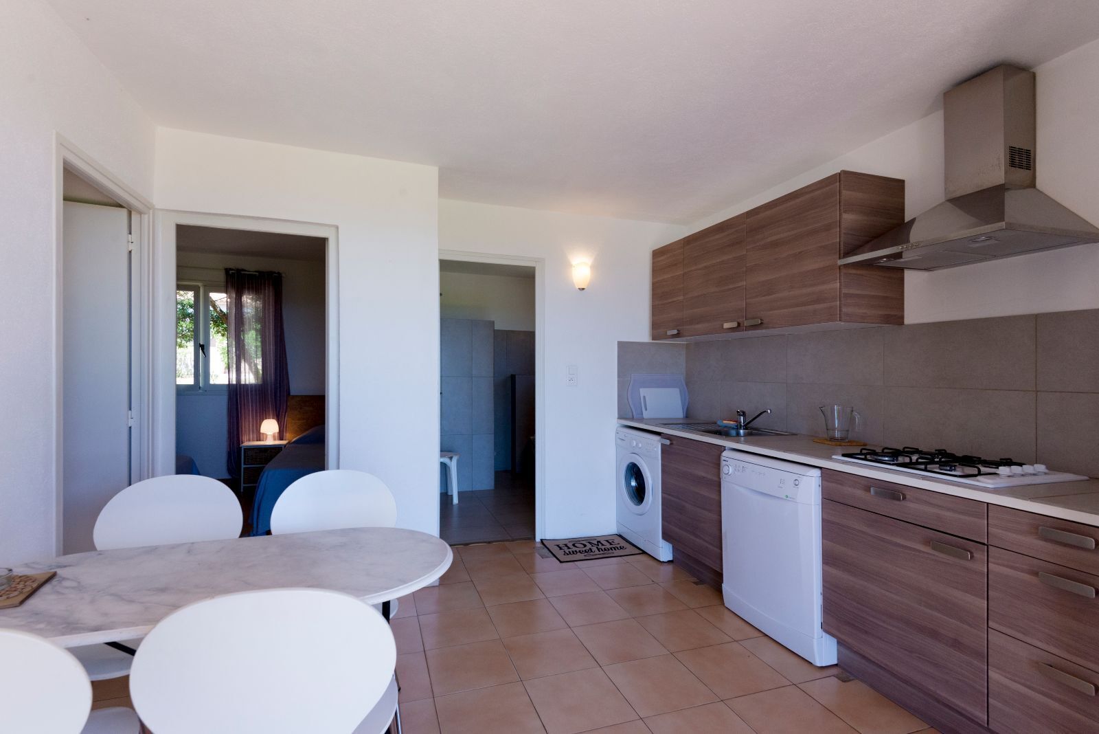 A compact kitchen with a gas stove, washing machine, and wooden cabinets.