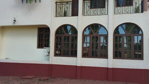 A two-story building with arched windows and balconies, flags, and a red and white facade. - KILIMANJARO PAZURI VILLAS(KPV) (Moshi)
