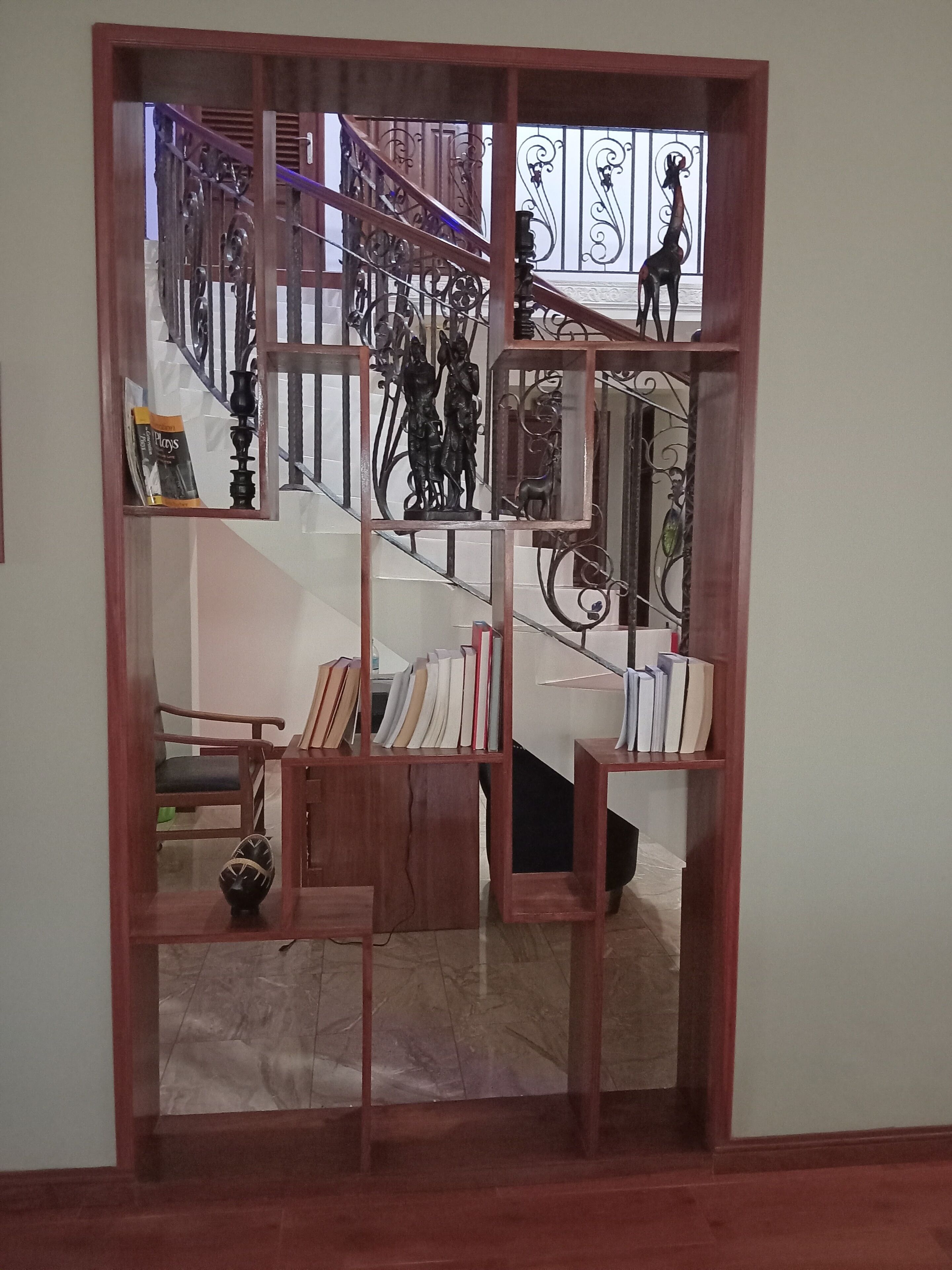 A wooden-framed view into a staircase with a metal railing and a giraffe sculpture.