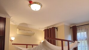 A single bed with a canopy, wooden headboard, and a bedside lamp. - KILIMANJARO PAZURI VILLAS(KPV) (Moshi)