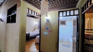 A narrow hallway with a bed and a window on the left, a wall with a light fixture and butterfly decorations, and a door on the right. - Enjoy the Peace and Nature of Jarabacoa (Jarabacoa)