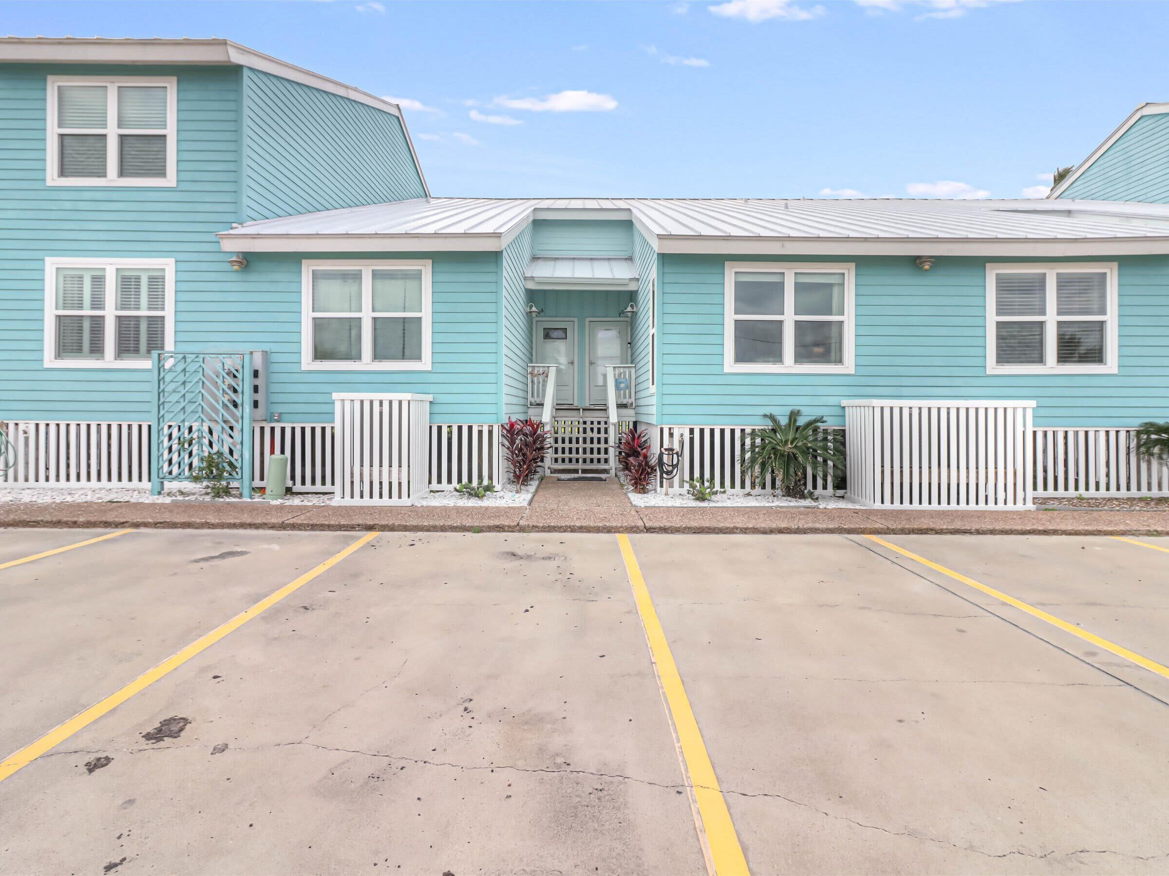 A two-story building with a flat roof, a front porch, and a white picket fence.