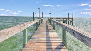 Une jetée en bois s’étendant sur une étendue d’eau calme, sous un ciel dégagé.