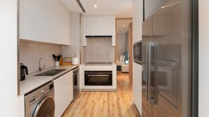 A modern kitchen with stainless steel appliances, a built-in oven, and a washing machine. - Modern 3BR Maid s Iconic Ain Dubai Views (Dubai)
