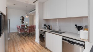 A modern kitchen with stainless steel appliances, a dishwasher, and a dining area with a table and chairs. - Modern 3BR Maid s Iconic Ain Dubai Views (Dubai)
