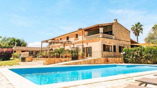 A two-story stone house with a swimming pool, surrounded by lush greenery and palm trees. - Ayurvila Wellness Retreat (Manacor)