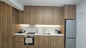 Une cuisine moderne avec des meubles en bois, un évier en acier inoxydable, un four encastré et un réfrigérateur.