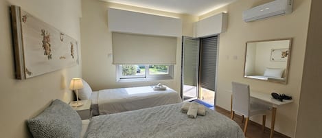 A bedroom with a bed, bedside tables, a desk, a chair, a window, and a mirror.