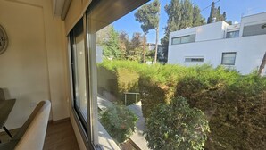 Un balcon donnant sur un jardin et un bâtiment moderne.