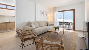A modern living room with a sofa, wicker chairs, a coffee table, and a TV. - Villa Los Altos Alene 10B by Escape Home (Playa Blanca)