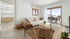 Een moderne woonkamer met een bank, rieten stoelen, een salontafel en een televisie.