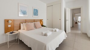 Une chambre à coucher avec une tête de lit en bois, une table de chevet avec une lampe et un lit recouvert de draps blancs et agrémenté de serviettes pliées.