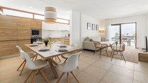 A modern kitchen with wooden cabinets, a dining table set for four, and a living area with a sofa and chairs. - Villa Los Altos Yaiza 9A by Escape Home (Playa Blanca)