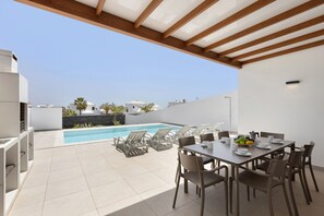 A rooftop terrace with a pool, dining area, and lounge chairs. - Villa Los Altos Yaiza 9A by Escape Home (Playa Blanca)