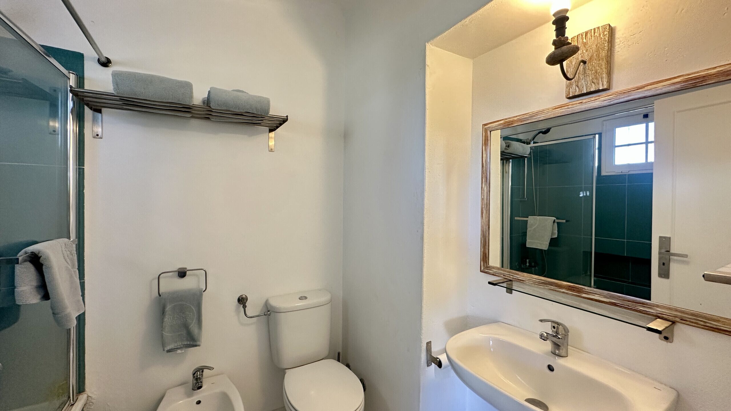 A bathroom with a toilet, bidet, sink, and a glass shower enclosure.