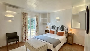 Une chambre à coucher avec un lit, des tables de chevet, une chaise et une fenêtre avec des rideaux.