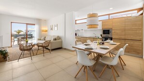 Eine moderne Küche mit Essbereich, einer Couch und Blick ins Freie.