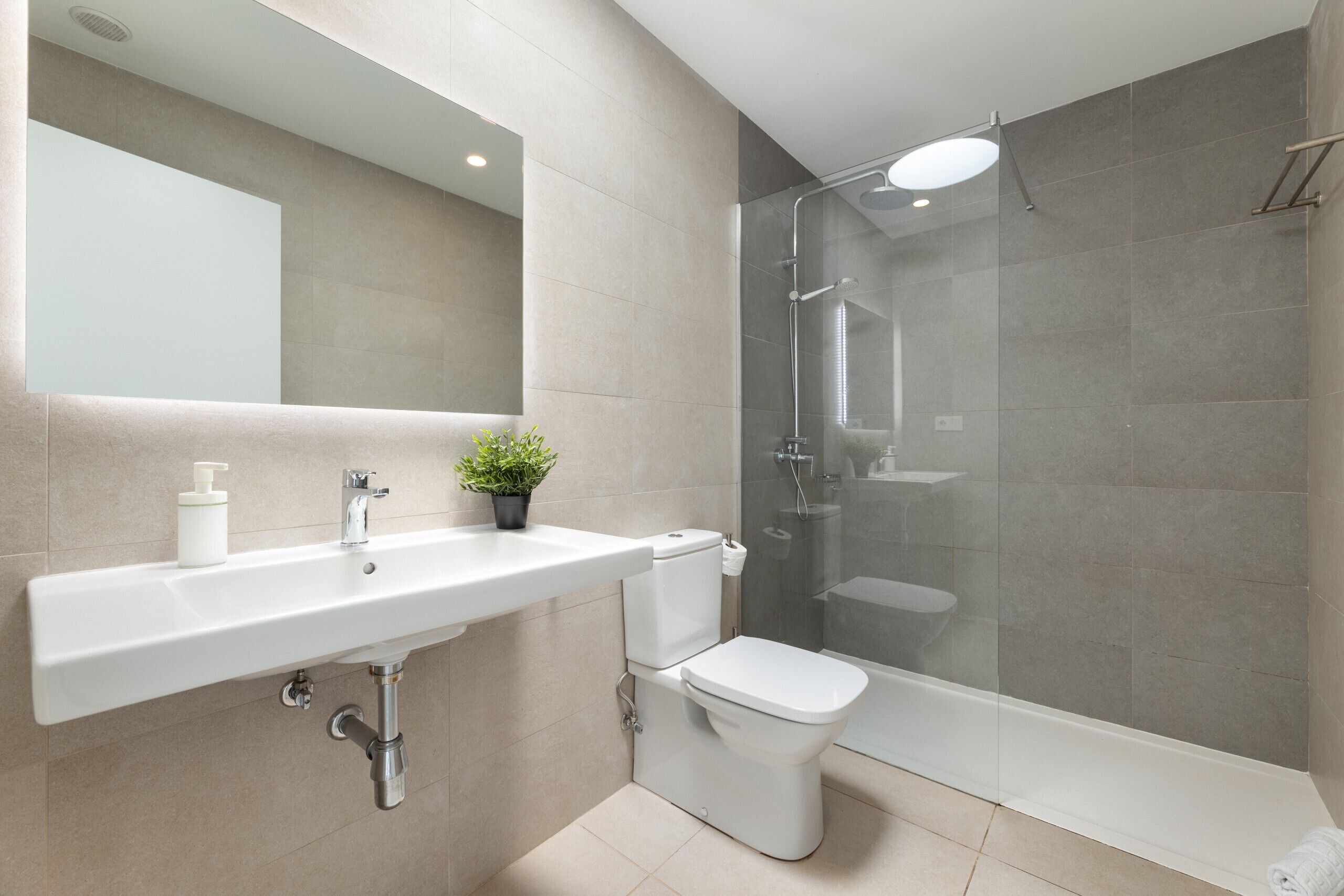 Een moderne badkamer met een wastafel, toilet en douchecabine met glazen wanden.