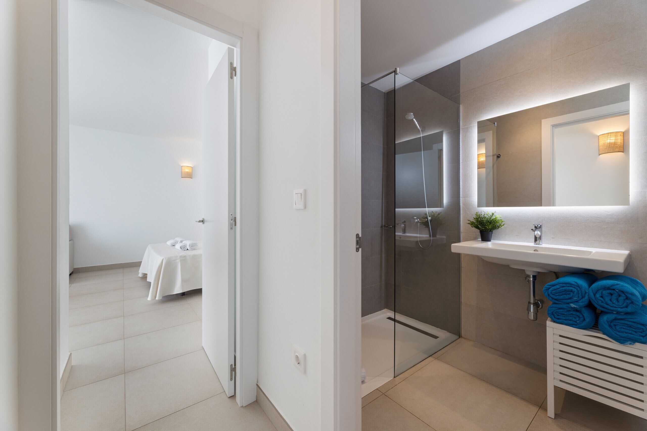 A modern bathroom with a glass shower enclosure, a white sink with a mirror, and a towel rack with towels.