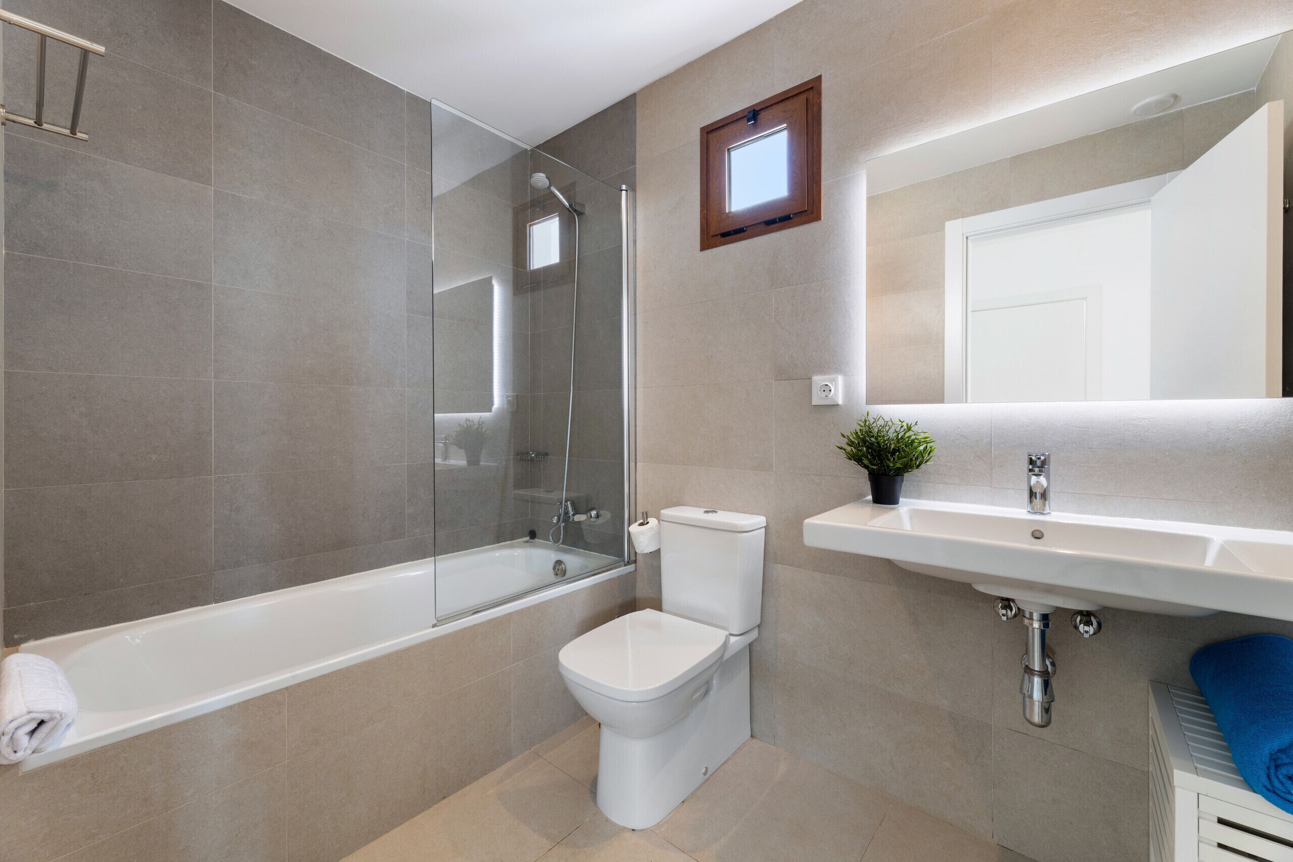 A modern bathroom with a glass-enclosed shower, a toilet, and a sink.