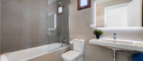 A modern bathroom with a glass-enclosed shower, a toilet, and a sink.