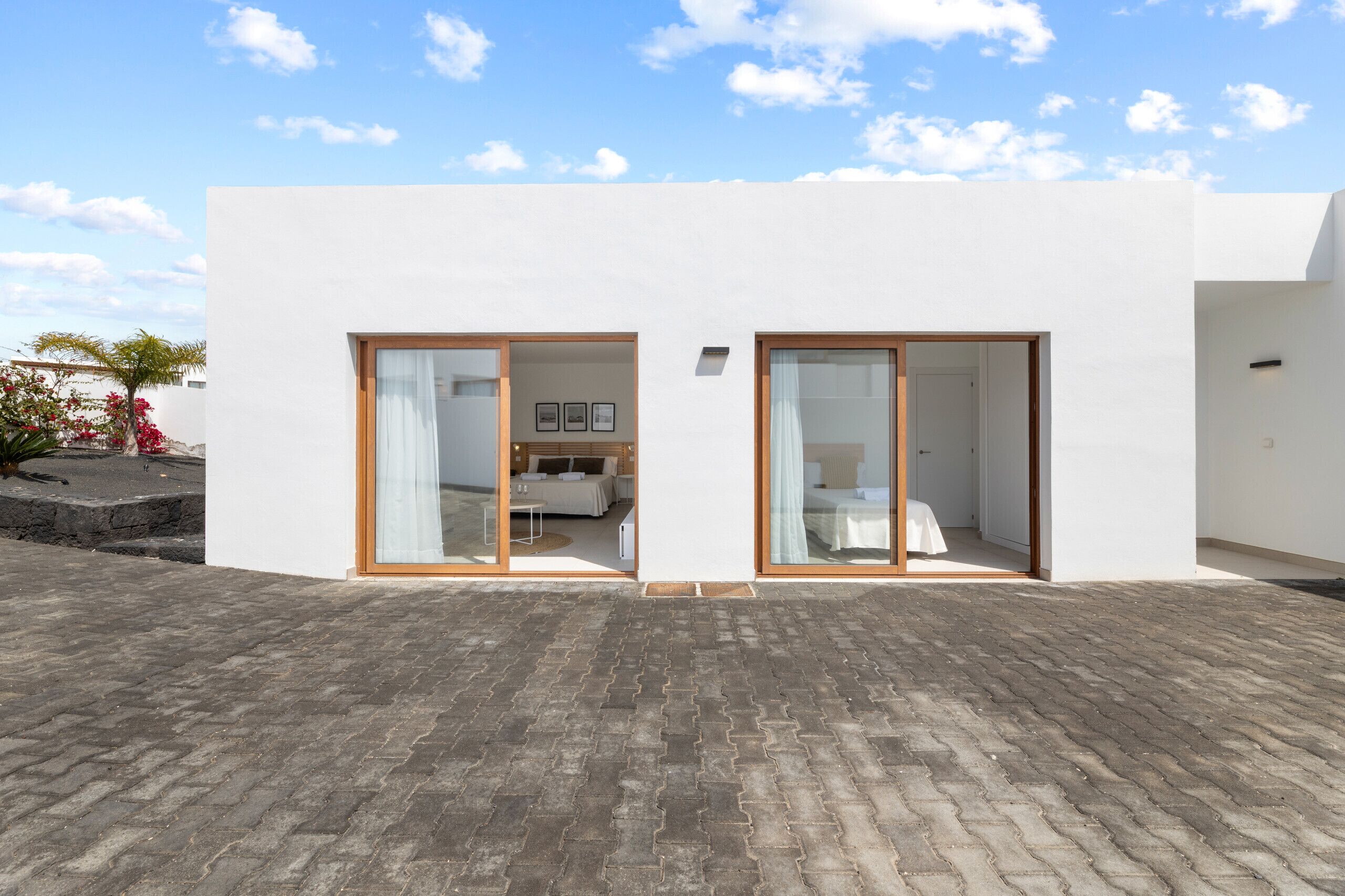 Un edificio moderno con dos grandes puertas correderas de vidrio que dan a un dormitorio con cama y una mesita.