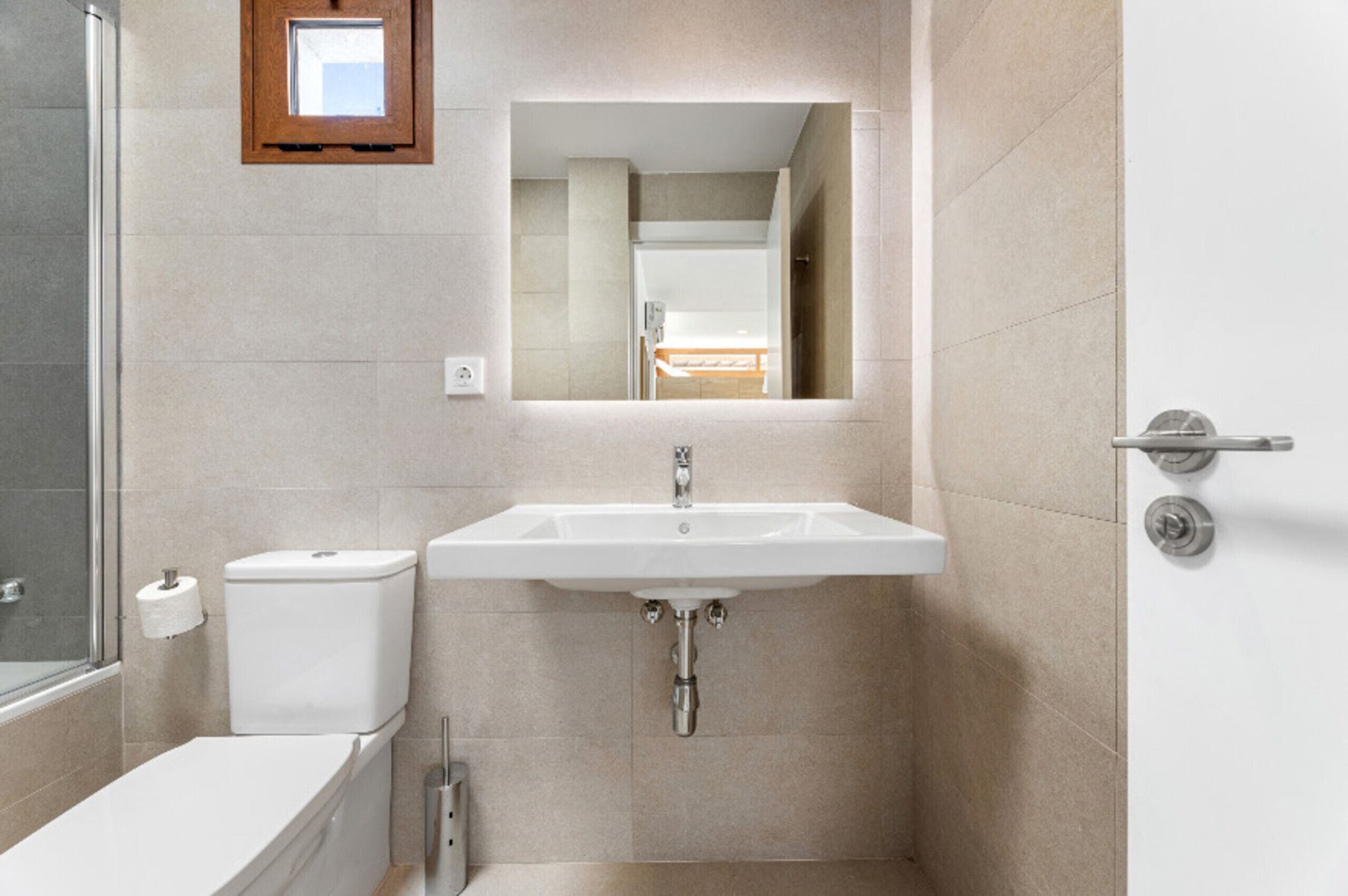 Un baño con lavamanos, inodoro y ducha blancos.