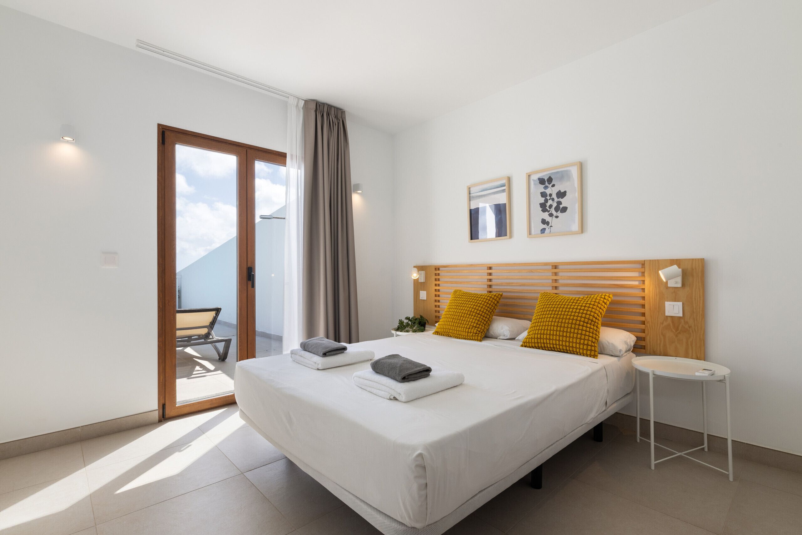 Un dormitorio moderno con una cama grande, una mesita de noche pequeña y vistas al exterior.