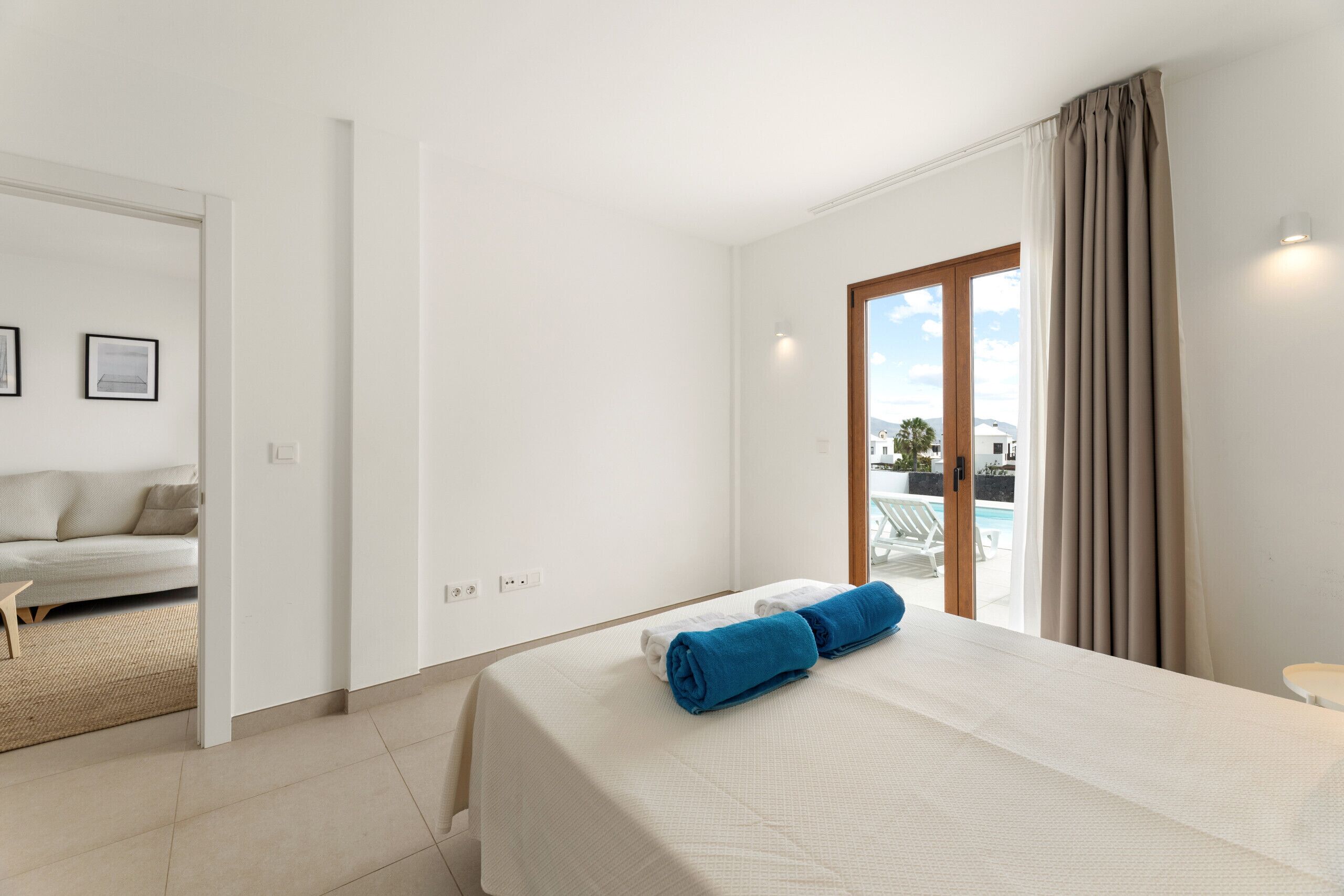 Una habitación de hotel con cama, vistas a la piscina y un balcón.