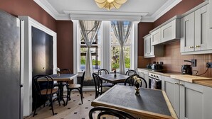 A modern kitchen with white cabinets, a wooden countertop, and a dining area with black chairs and a table. - Clarence House (Londonderry)