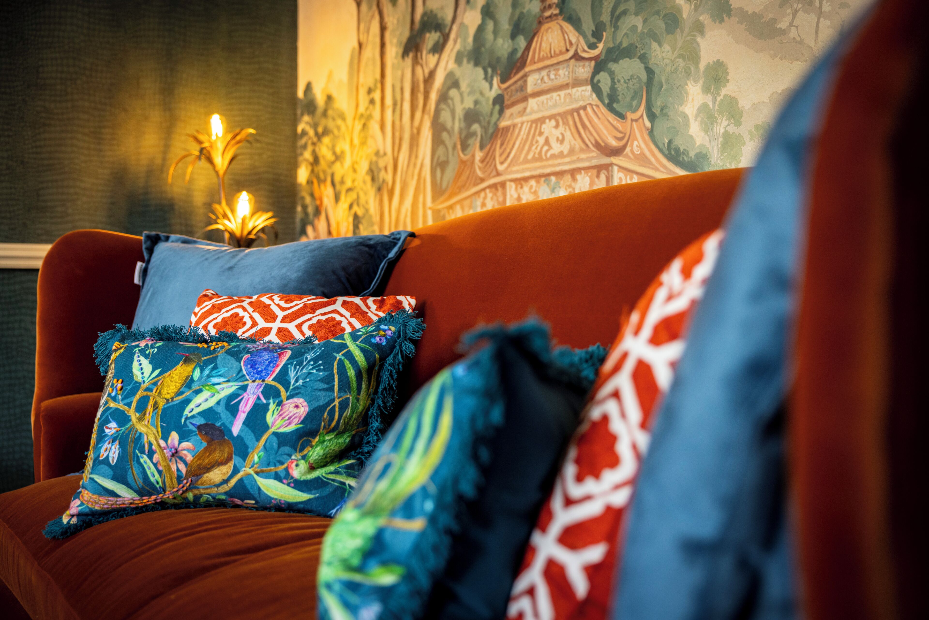 A sofa with colorful pillows and a wall with a mural.