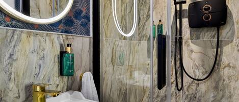 A bathroom with a glass-enclosed shower, a white sink, and a marble wall.
