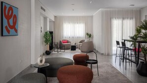 A modern living room with a sofa, ottomans, a coffee table, and a dining area with chairs and a table. - Livingville East (New Cairo)