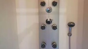 A modern shower enclosure with multiple nozzles and a soap dispenser.