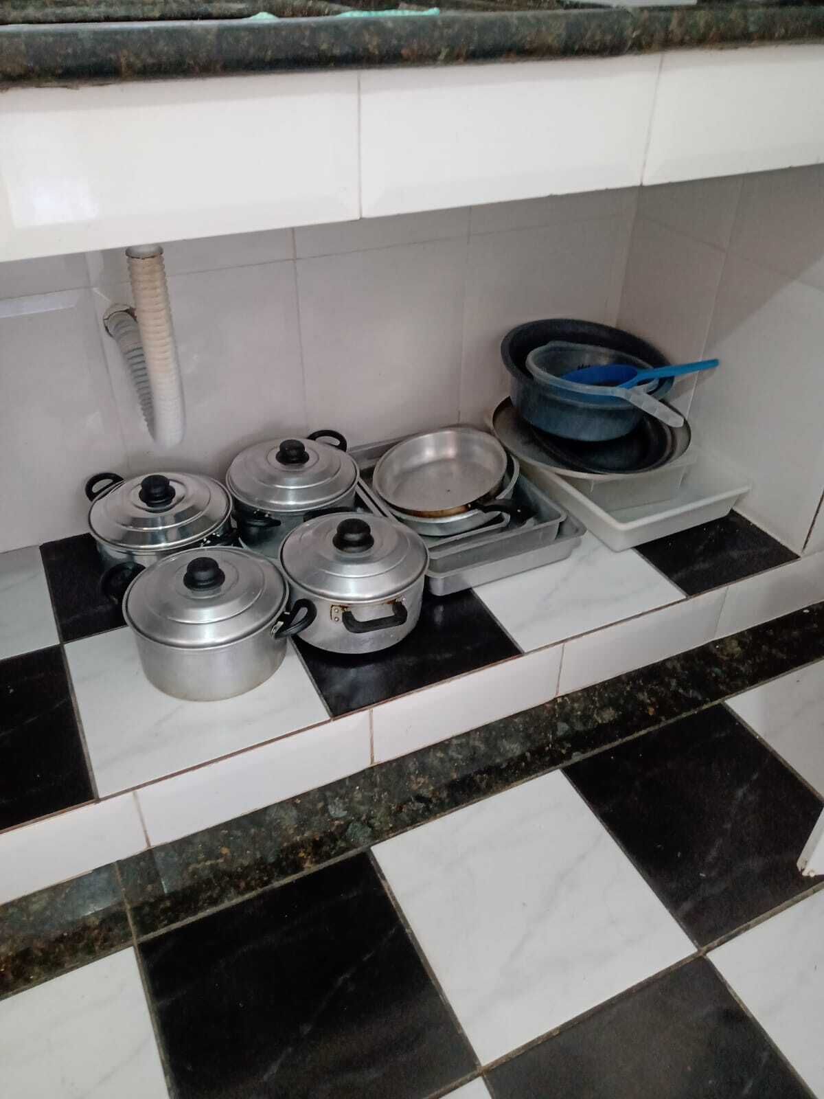 Una cocina con estufa a gas, ollas, sartenes y una espátula azul.