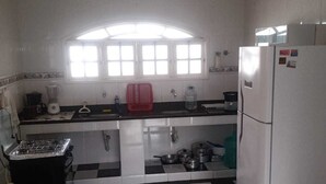 Een keuken met een zwart-wit geruite vloer, een gasfornuis, een koelkast en een raam boven de gootsteen.
